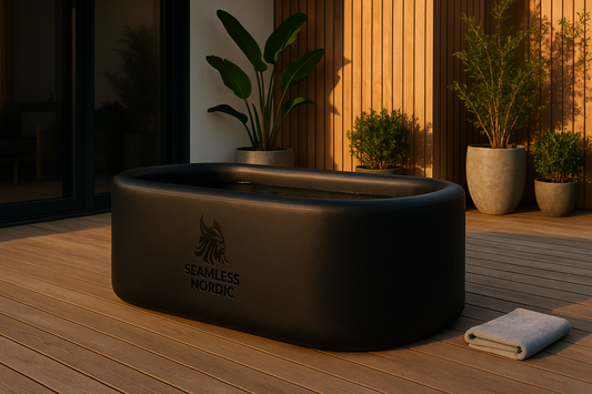 Black bathtub with 'Seamless Nordic' logo on a wooden deck with plants in the background